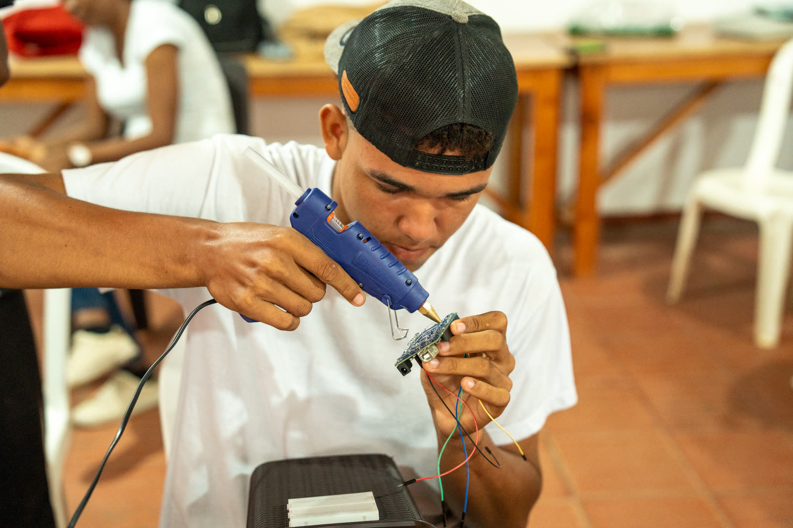 Estudiante ensambla cuidadosamente un dispositivo y comprueba sus conexiones.