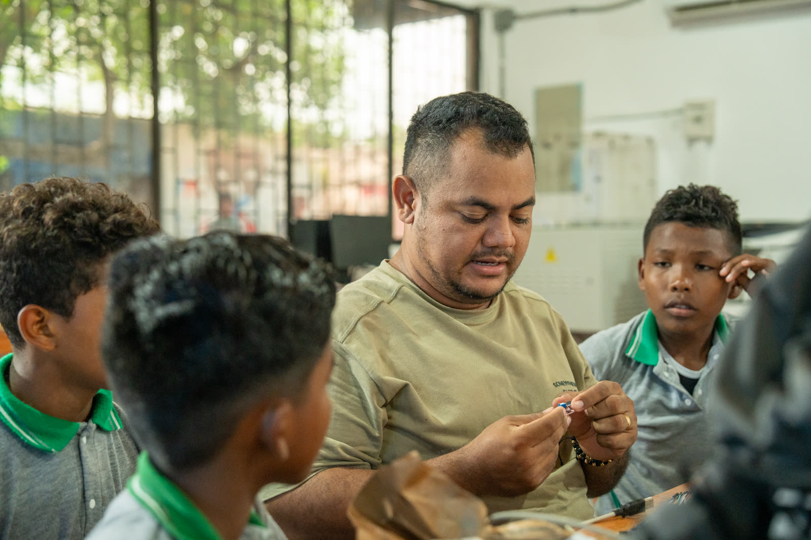 Estudiantes y docente ensamblan componentes electrónicos durante una práctica de aula.