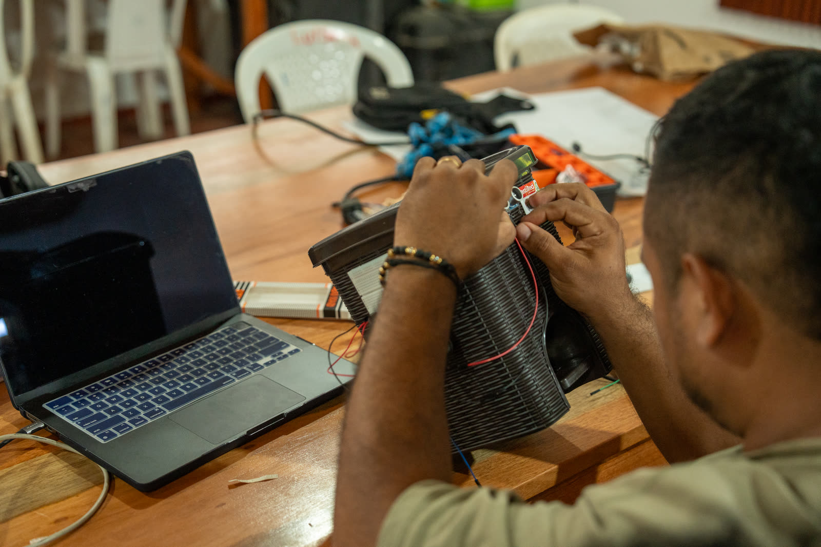 Estudiante utiliza herramientas para ensamblar y ajustar un sistema electrónico.