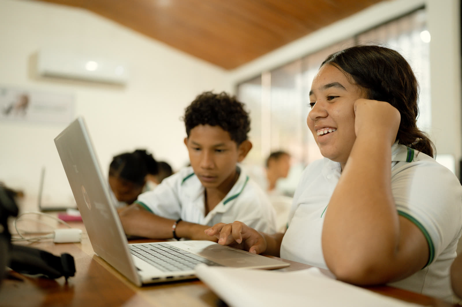 Estudiantes investigan y organizan información comunitaria en computadores.