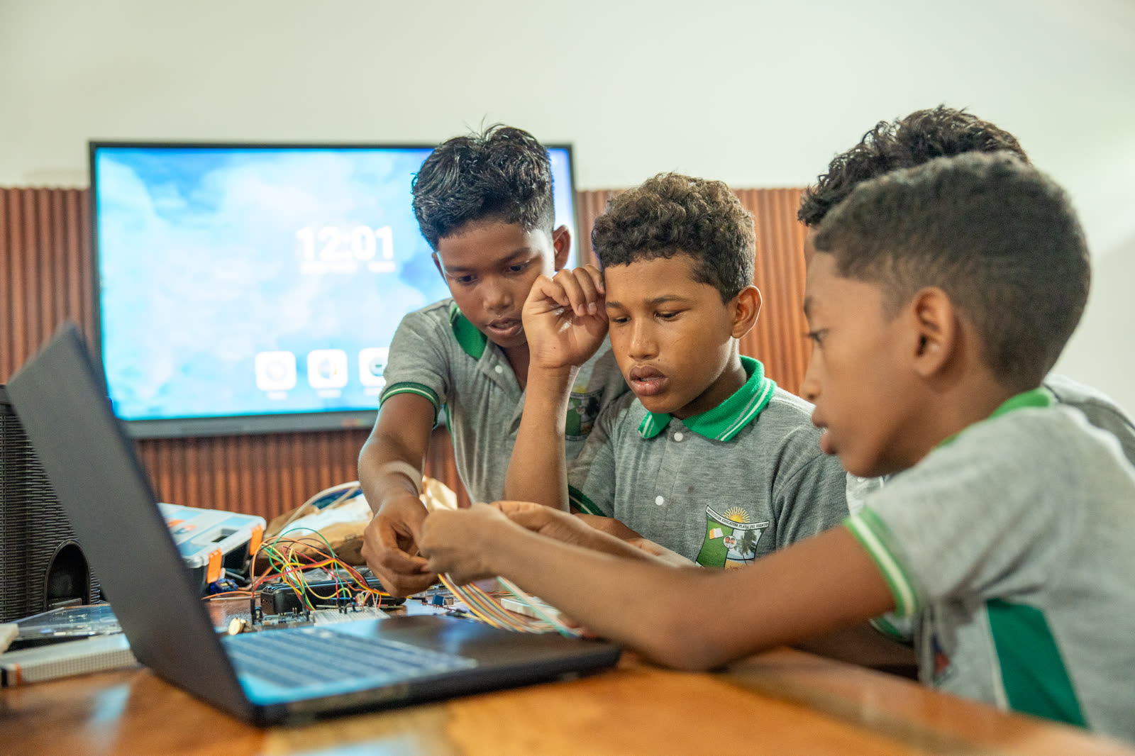 Estudiantes trabajan con un computador y componentes para resolver un reto tecnológico.